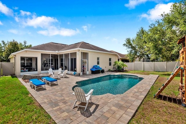 view of swimming pool featuring a playground, a sunroom, a yard, and a patio