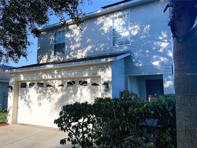 exterior space with driveway, an attached garage, and stucco siding