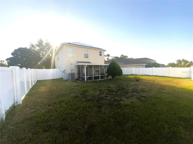 view of yard with central AC unit, a fenced backyard, and a sunroom