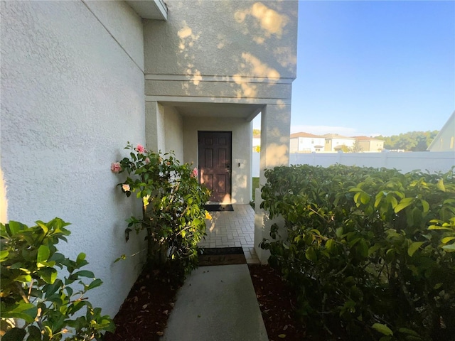 property entrance featuring fence and stucco siding