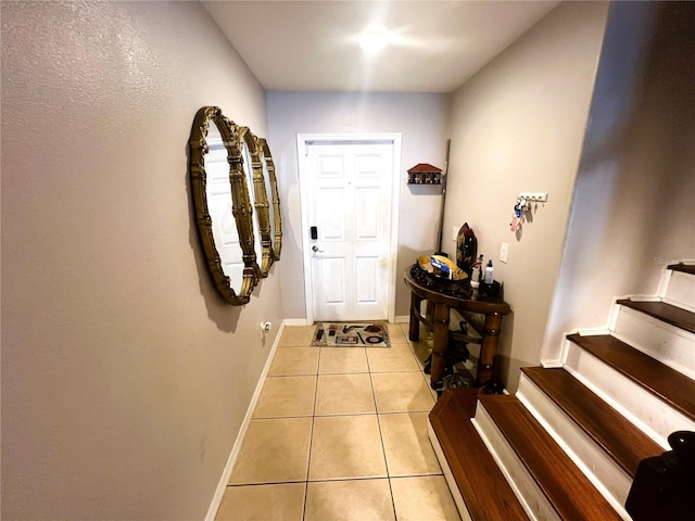 entryway with stairway, baseboards, and light tile patterned floors