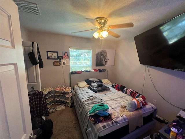 carpeted bedroom featuring a ceiling fan, visible vents, and a textured ceiling