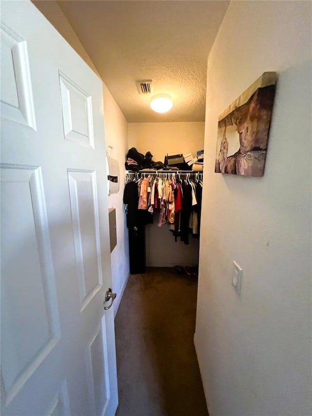 spacious closet with visible vents and dark carpet