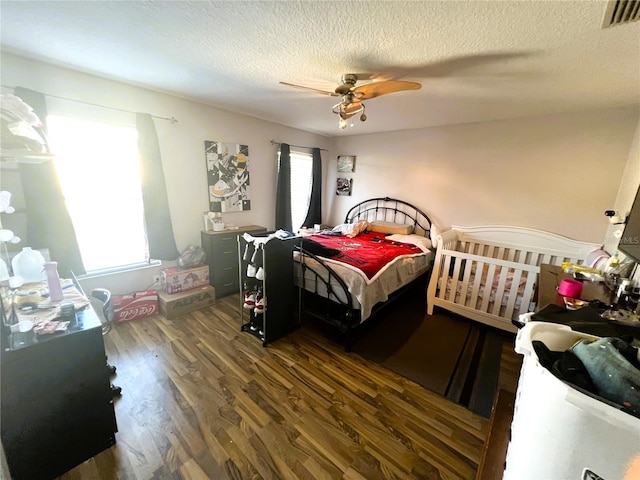 bedroom with a ceiling fan, dark wood-style flooring, visible vents, and a textured ceiling