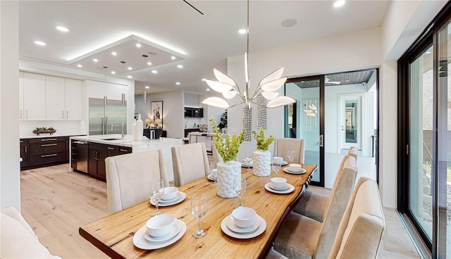 dining area featuring light hardwood / wood-style floors, sink, and a chandelier