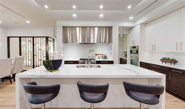 kitchen with a breakfast bar area, light stone countertops, and white cabinets