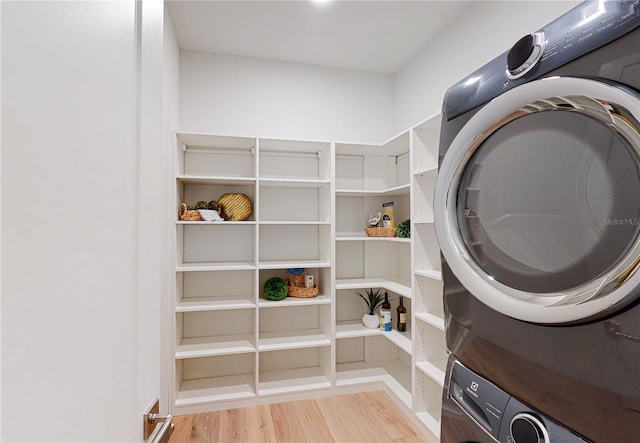 laundry area with stacked washing maching and dryer and hardwood / wood-style flooring