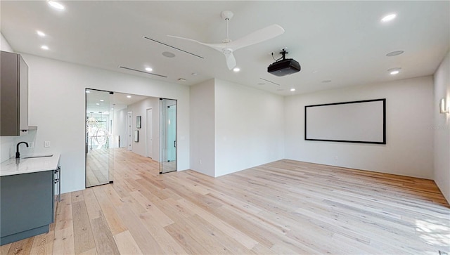 home theater room featuring light wood-type flooring, ceiling fan, and sink