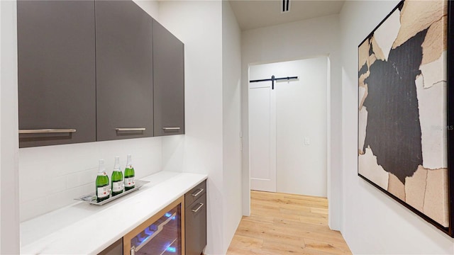 bar with beverage cooler and light wood-type flooring