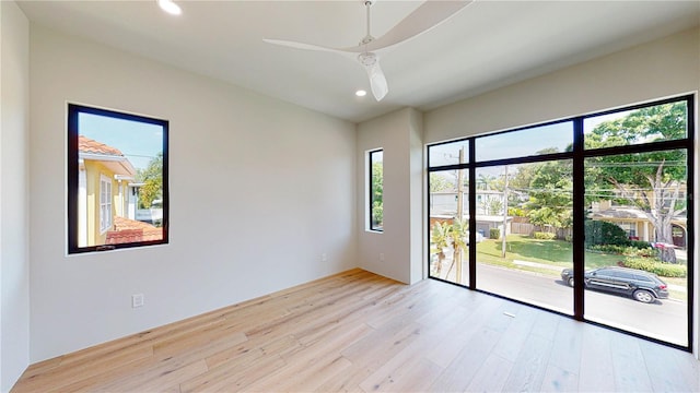 spare room with ceiling fan, a healthy amount of sunlight, and light hardwood / wood-style flooring