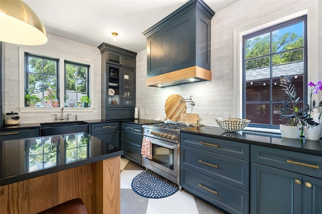 kitchen featuring a healthy amount of sunlight, high end range, sink, and custom range hood