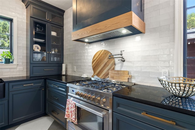 kitchen featuring backsplash, blue cabinetry, premium range hood, and stainless steel range