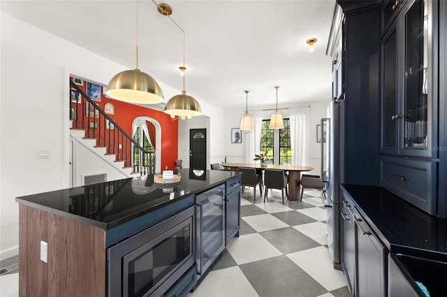 kitchen with hanging light fixtures, a kitchen island, beverage cooler, and appliances with stainless steel finishes