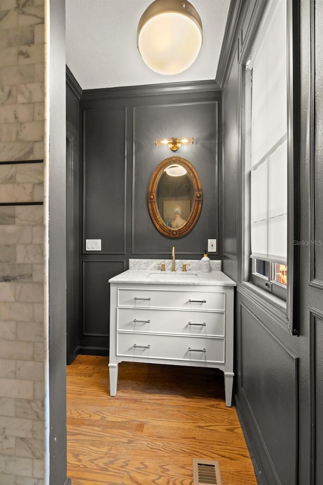 bathroom featuring vanity, wood-type flooring, and ornamental molding