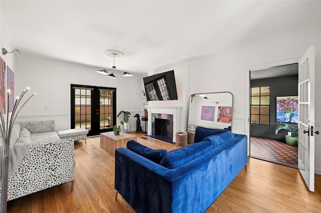 living room featuring light hardwood / wood-style floors, crown molding, and french doors