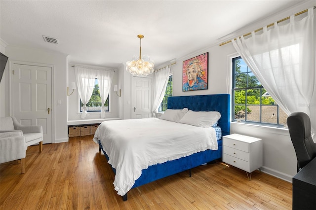 bedroom featuring an inviting chandelier and light wood-type flooring