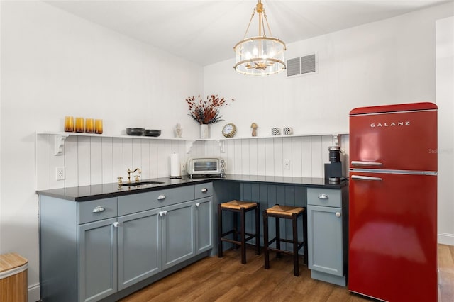 kitchen featuring an inviting chandelier, refrigerator, sink, tasteful backsplash, and dark hardwood / wood-style flooring