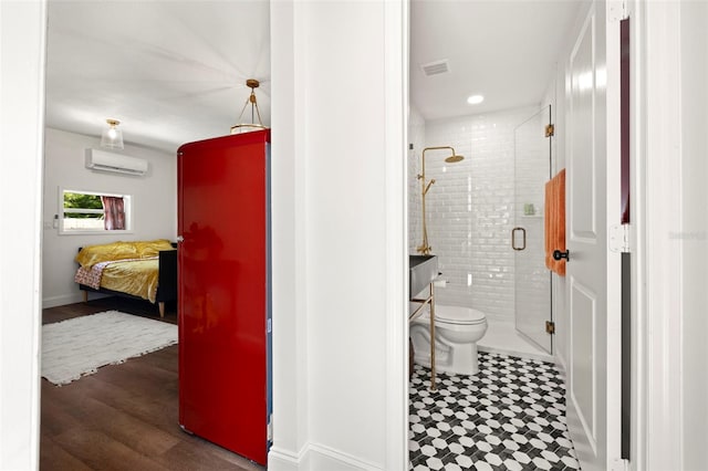 bathroom featuring a wall unit AC, a shower with door, and toilet