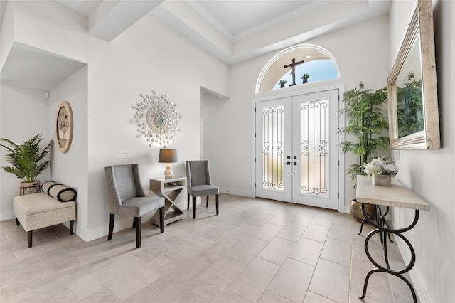 foyer entrance featuring french doors, a towering ceiling, and ornamental molding