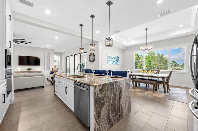 kitchen featuring sink, stainless steel appliances, light stone counters, an island with sink, and white cabinets