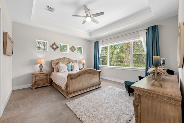 bedroom with ceiling fan, a raised ceiling, and ornamental molding