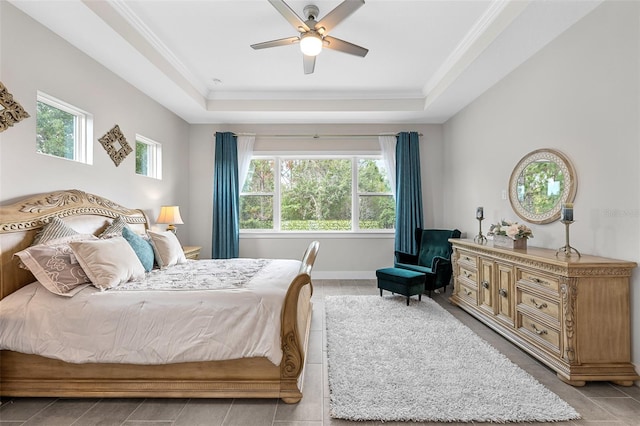 bedroom featuring ceiling fan, crown molding, multiple windows, and a tray ceiling