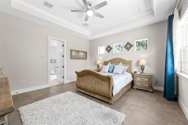 bedroom with ensuite bathroom, a raised ceiling, and ceiling fan