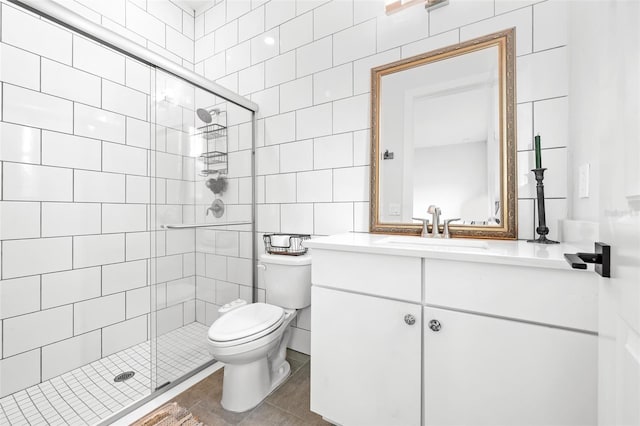 bathroom with vanity, a shower with door, toilet, and tile walls