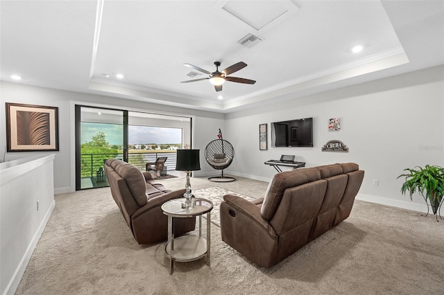 carpeted living room featuring a tray ceiling, ceiling fan, and crown molding