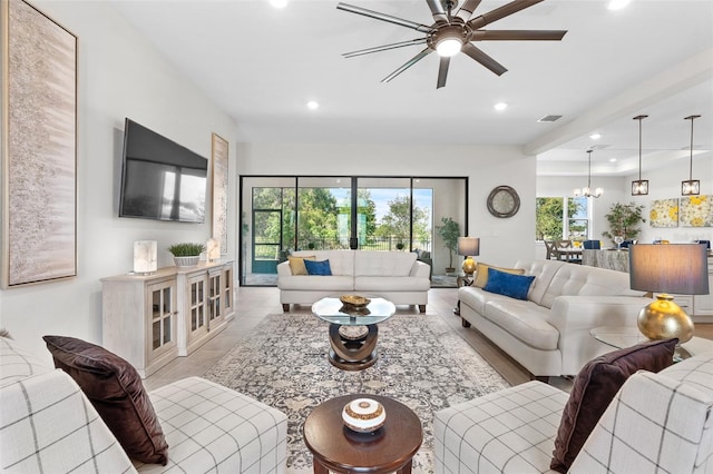 living room with ceiling fan with notable chandelier