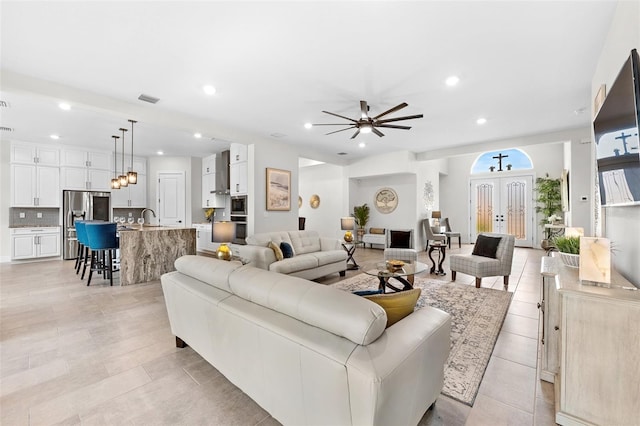 tiled living room with ceiling fan and sink