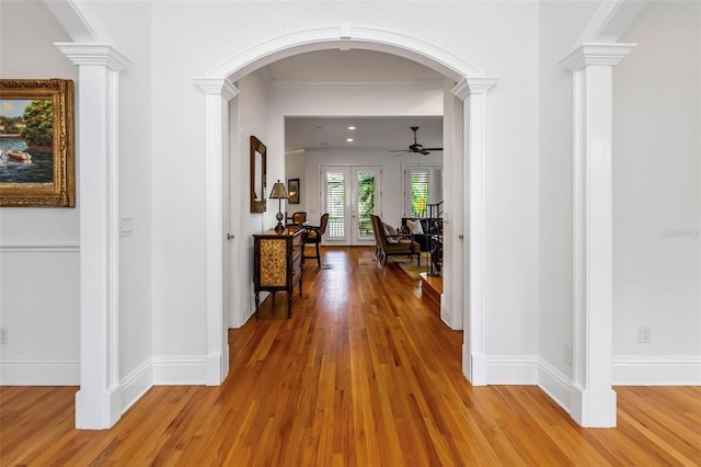 corridor featuring hardwood / wood-style floors, ornate columns, french doors, and ornamental molding