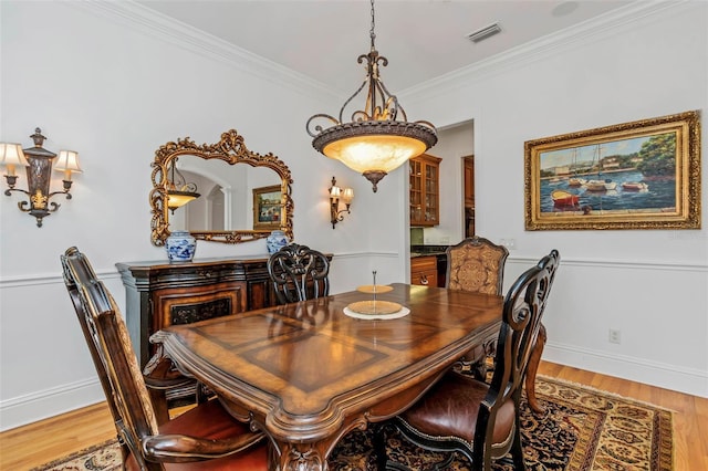 dining area featuring wood-type flooring and ornamental molding