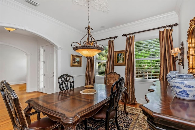 dining space featuring light hardwood / wood-style floors, ornate columns, and ornamental molding