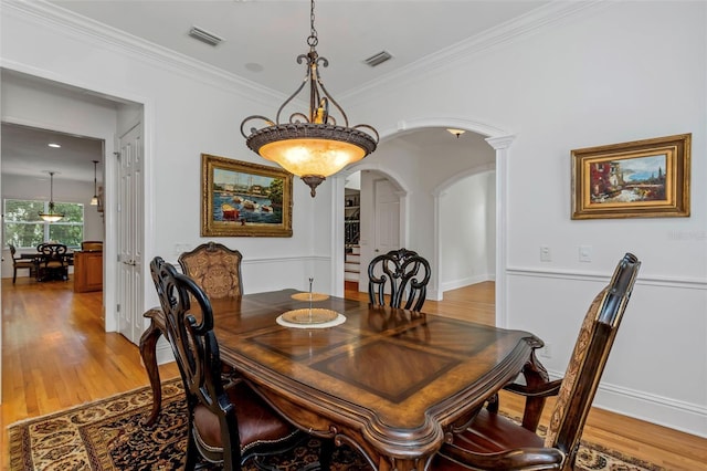 dining room with hardwood / wood-style flooring, ornate columns, and crown molding