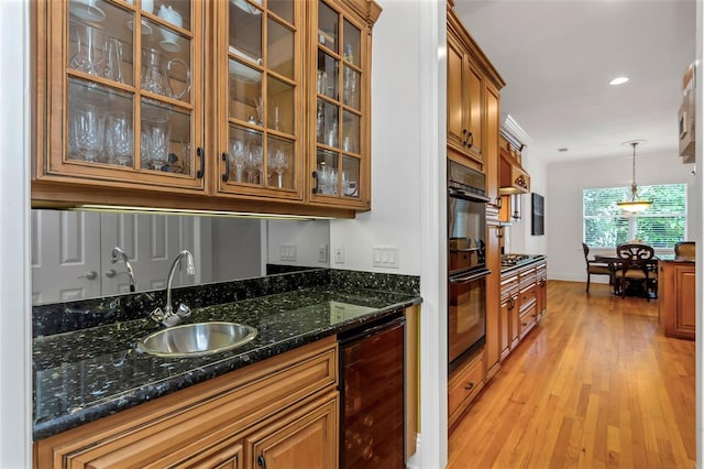 kitchen with light wood-type flooring, dark stone counters, beverage cooler, sink, and pendant lighting