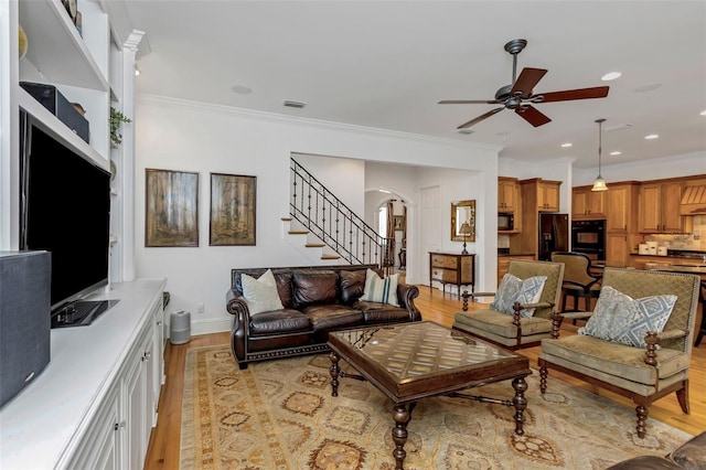 living room featuring ceiling fan, light wood-type flooring, and ornamental molding