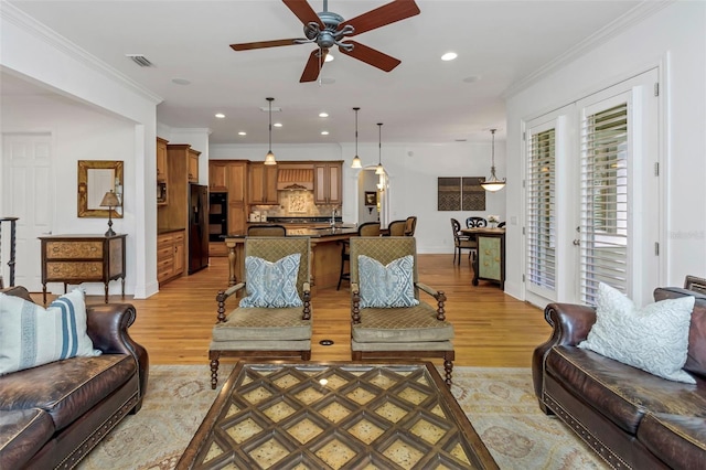 living room with light hardwood / wood-style floors, ceiling fan, and crown molding