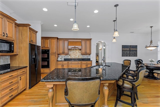 kitchen with a kitchen bar, tasteful backsplash, black appliances, hanging light fixtures, and a large island