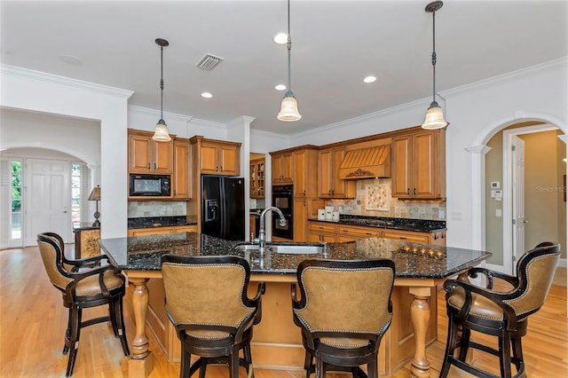 kitchen with sink, a breakfast bar area, a spacious island, and black appliances