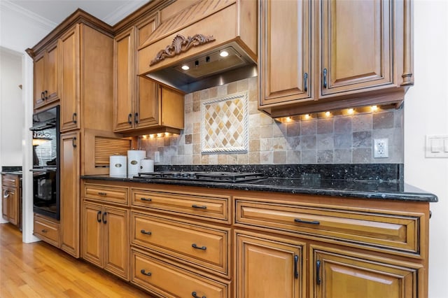 kitchen with black appliances, decorative backsplash, light hardwood / wood-style floors, and dark stone counters