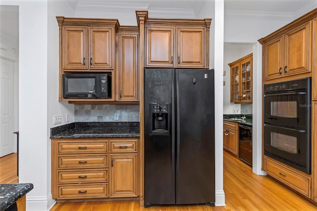 kitchen featuring dark stone counters, black appliances, sink, light wood-type flooring, and beverage cooler