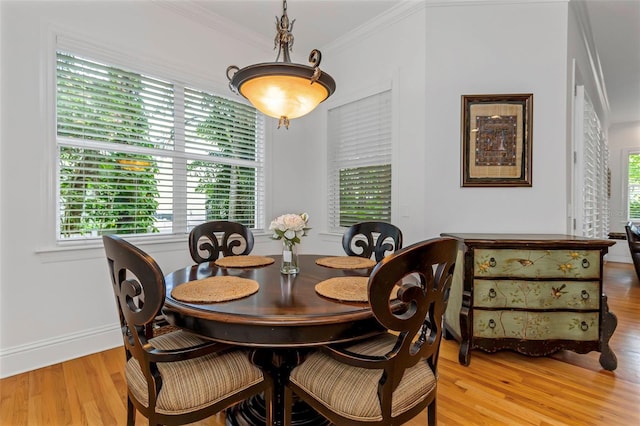 dining space with crown molding and light hardwood / wood-style flooring