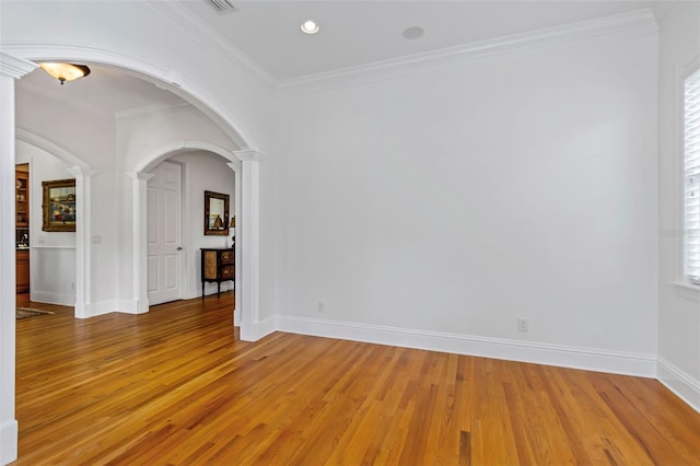 spare room featuring wood-type flooring, ornate columns, and crown molding