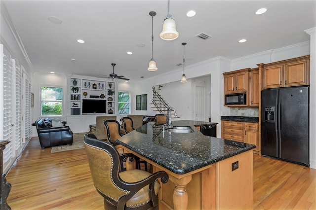 kitchen featuring ceiling fan, sink, an island with sink, pendant lighting, and black appliances