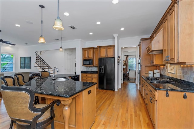 kitchen with pendant lighting, black appliances, a spacious island, sink, and tasteful backsplash