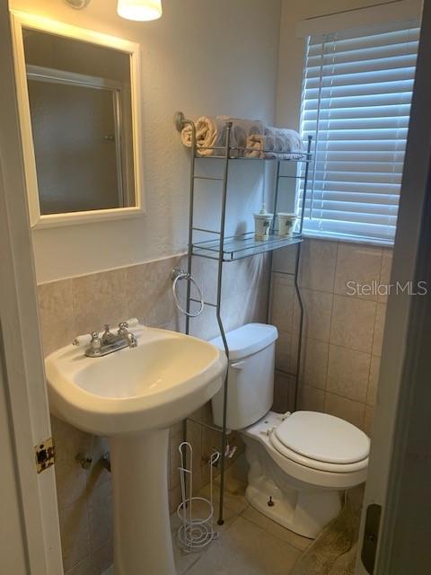 bathroom with tile walls and toilet