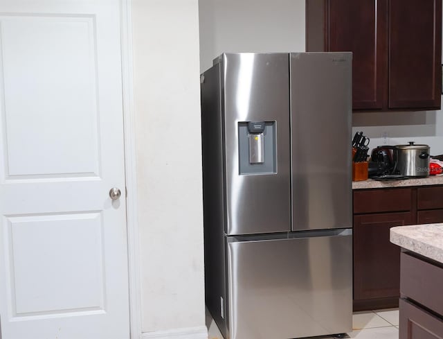 kitchen featuring stainless steel fridge, dark brown cabinets, and light tile patterned floors