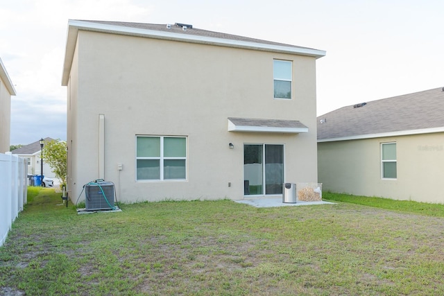 back of house featuring central AC unit and a yard