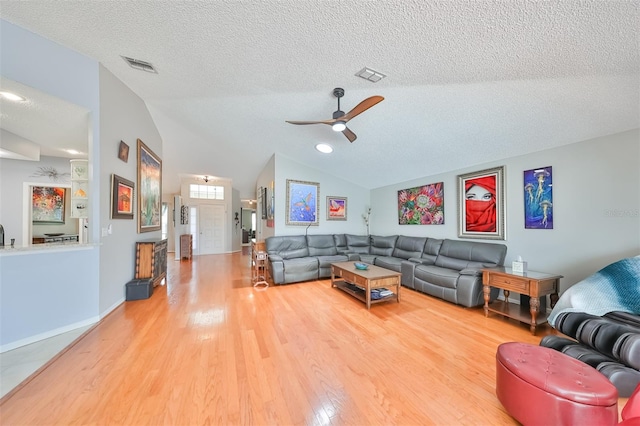 living room with ceiling fan, wood-type flooring, lofted ceiling, and a textured ceiling